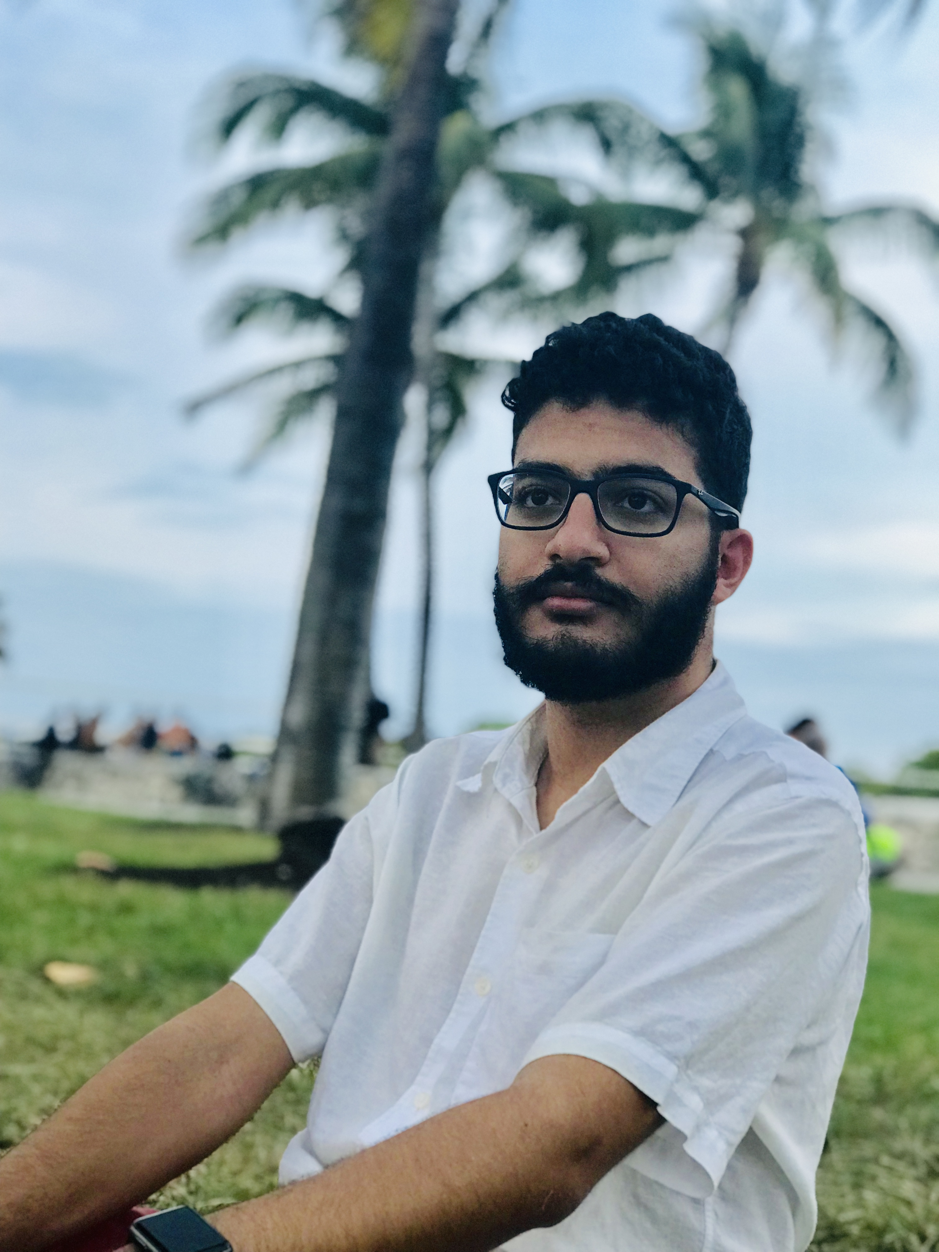 Me sitting down with palm trees in the background in Miami, April 2019