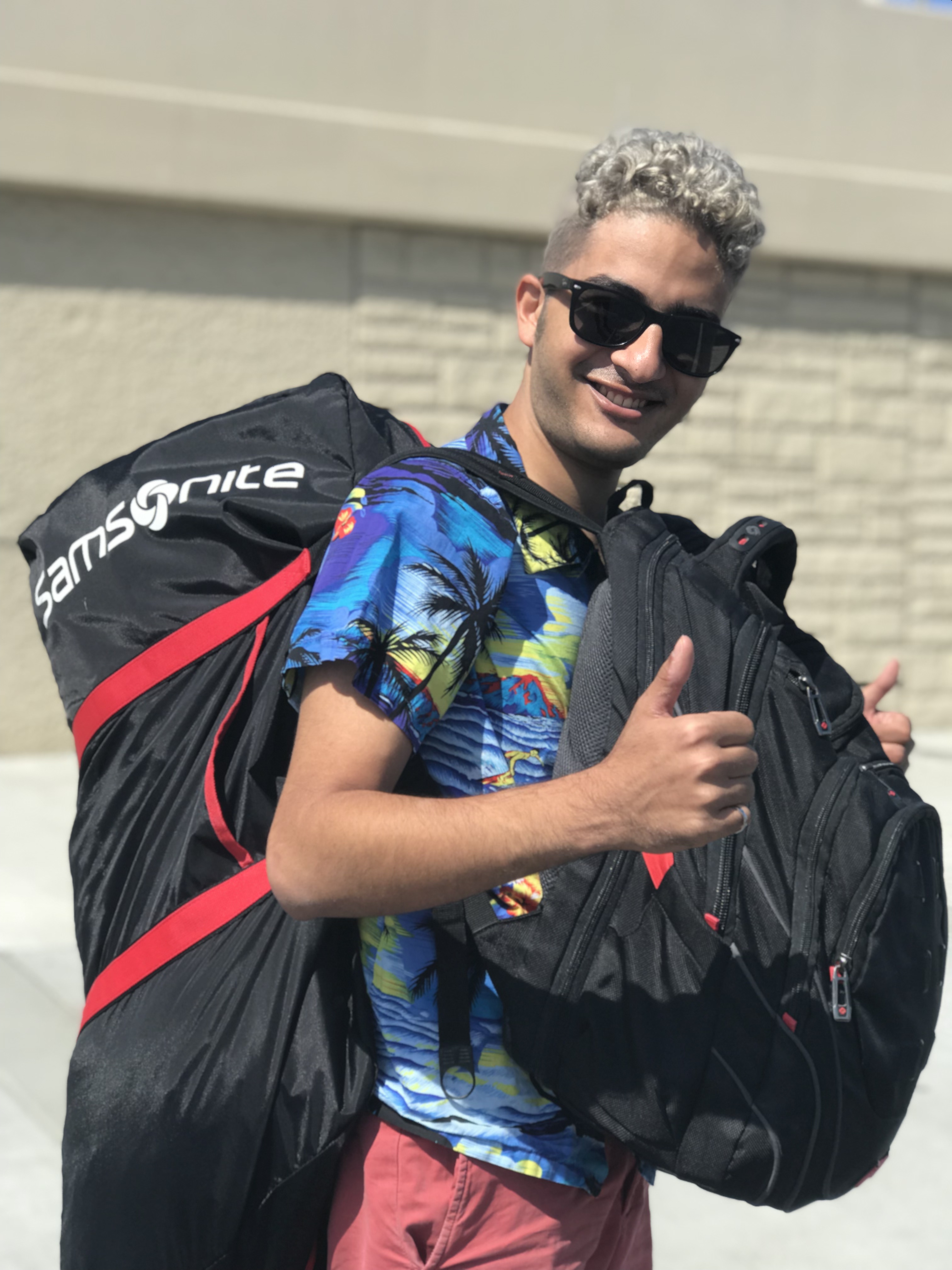 Me with two thumbs up carrying two backpacks in San Francisco, August 2019